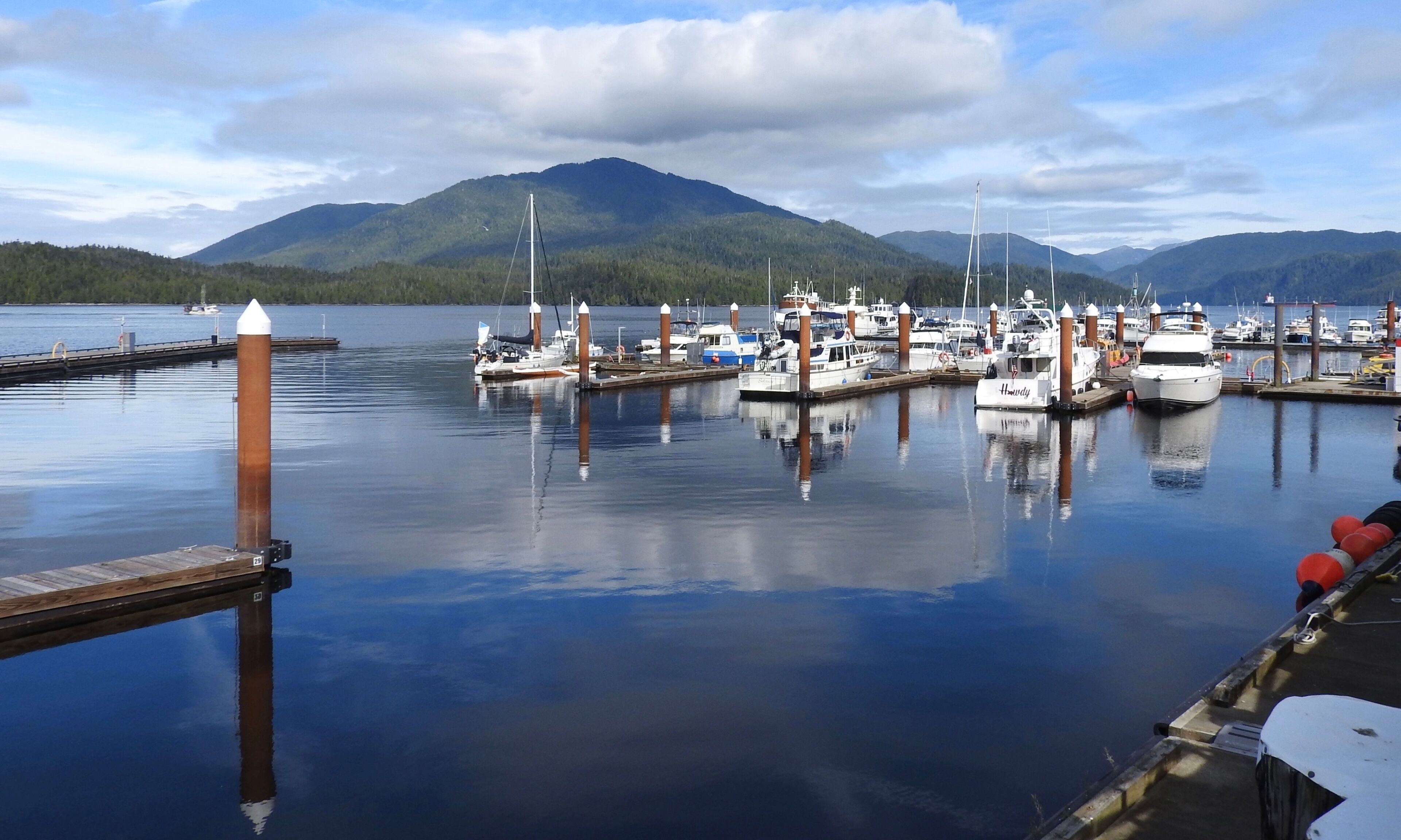 A marina with boats docked, surrounded by mountains and a clear sky.