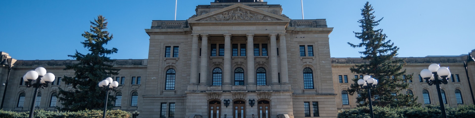 Un grand bâtiment gouvernemental doté d’un dôme central, de deux drapeaux et d’une façade symétrique.