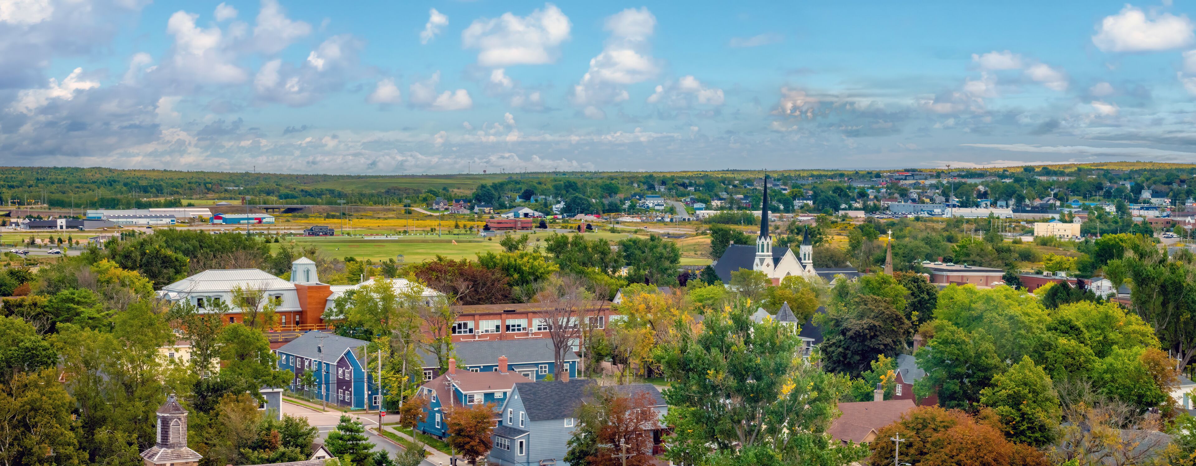 A town with a prominent church steeple, a large industrial area, and residential houses.