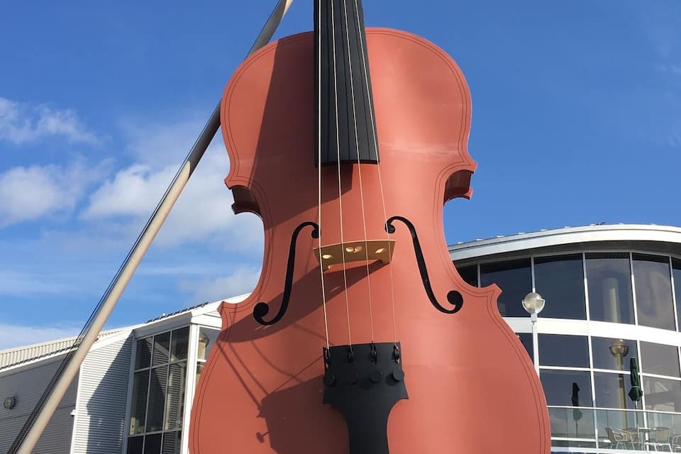 A large red violin sculpture in front of a modern building.