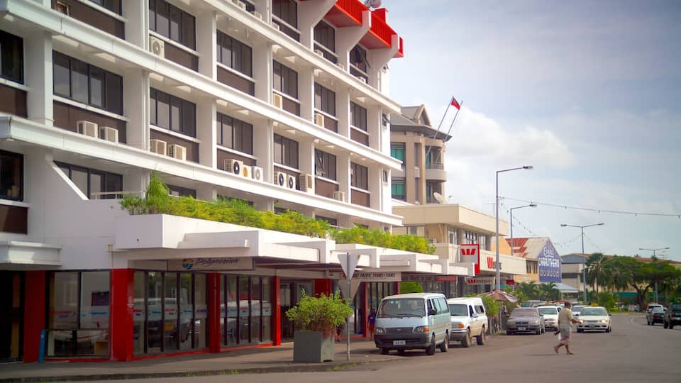 Een meerhoog gebouw met balkons, een rode vlag en geparkeerde auto's op straat.