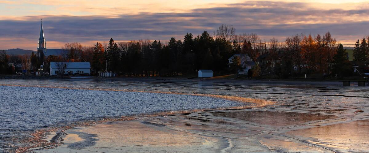 A frozen river with a church spire in the background.