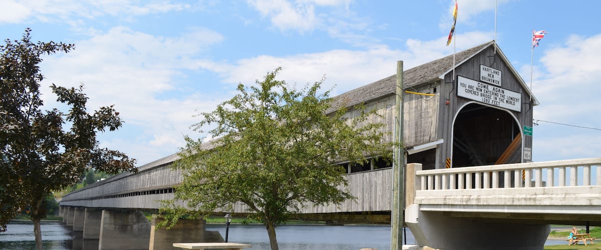 A covered bridge over a river with a sign indicating it is the longest covered bridge in the world.