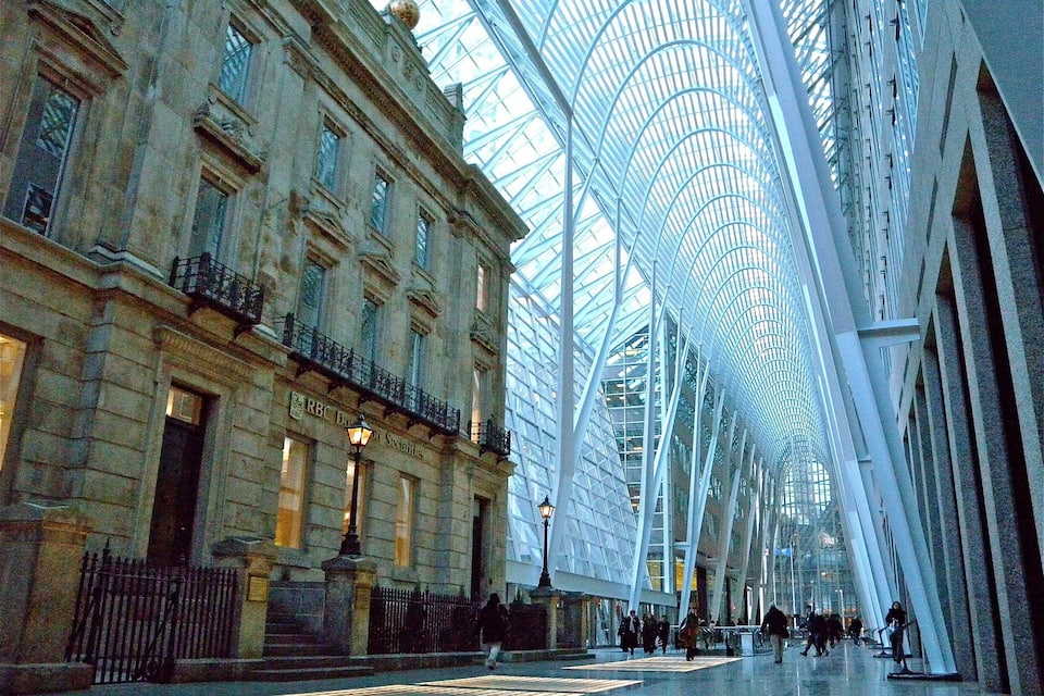 Une structure moderne en verre, avec un bâtiment historique situé à côté.