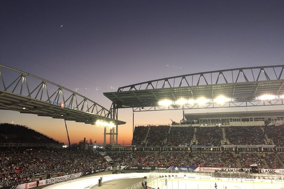 Un estadio grande con una pista de hielo curva, rodeado por una multitud de espectadores.