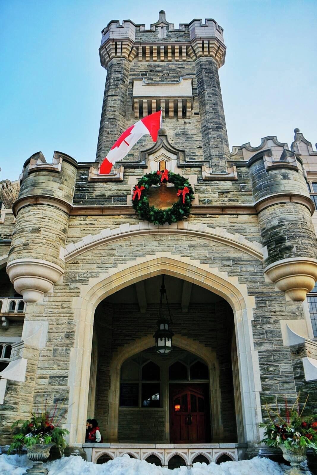 Ein Steinhaus mit großem Bogenportal, einer Flagge und einem Kranz.