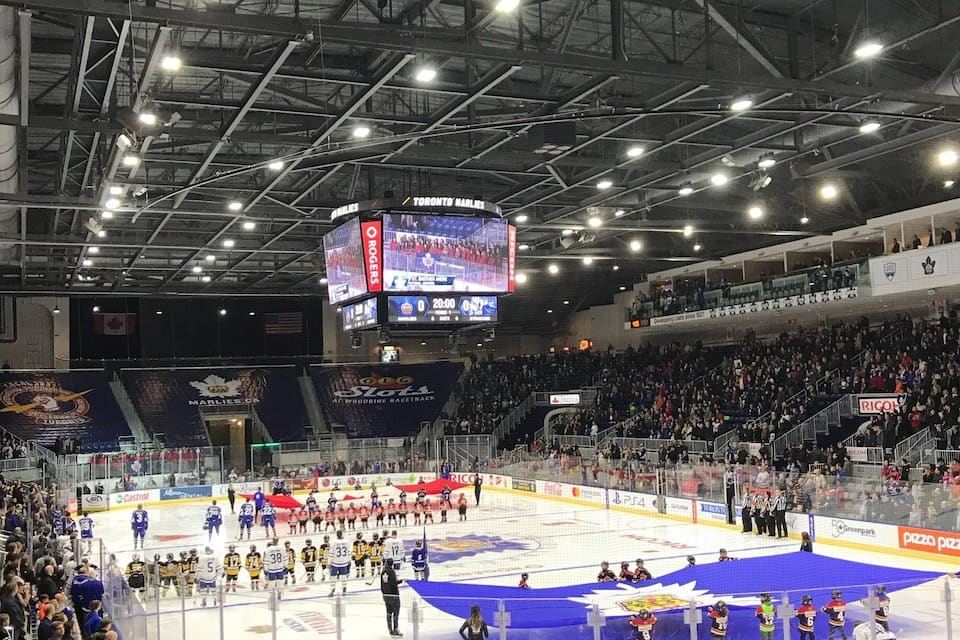Una pista de hielo cubierta para hockey con marcador, publicidad y espectadores.