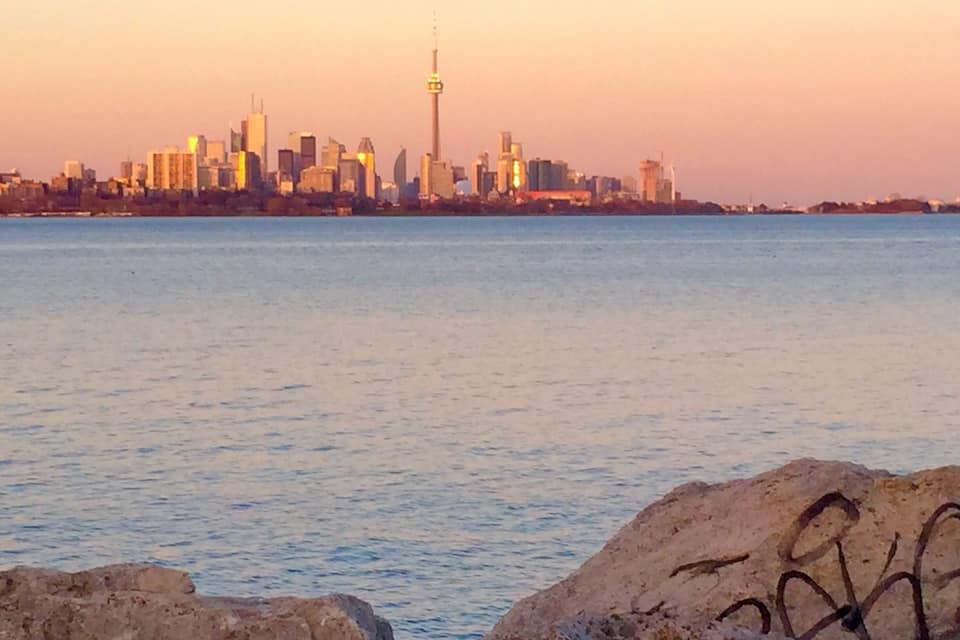 A city skyline at sunset with a prominent tower in the center.