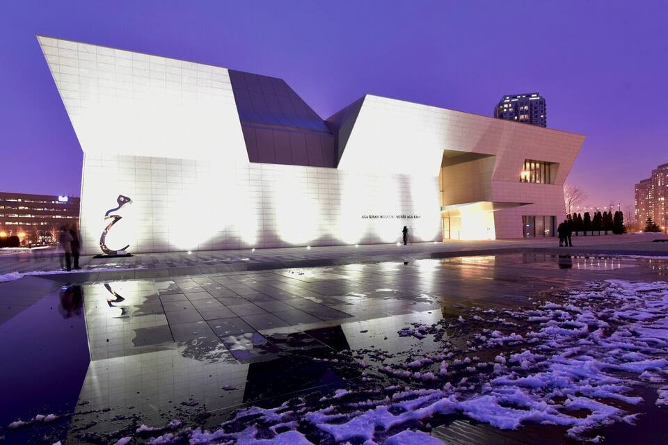 Un edificio moderno con un diseño angular único, iluminado al anochecer.