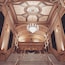 A grand staircase leading to a theater's ornate ceiling with a chandelier.