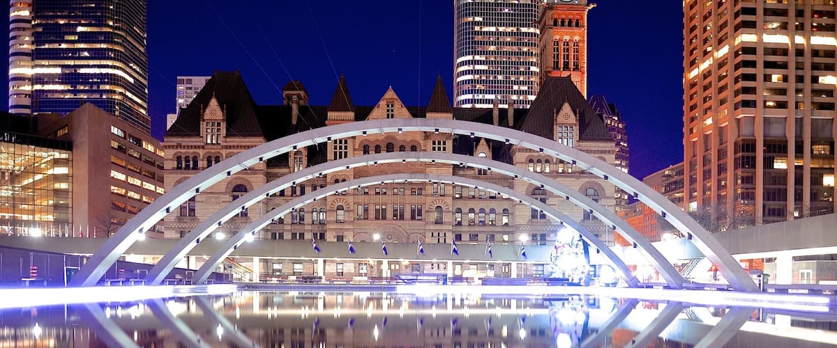 A modern bridge with a reflection in the water, surrounded by historic buildings and tall skyscrapers.
