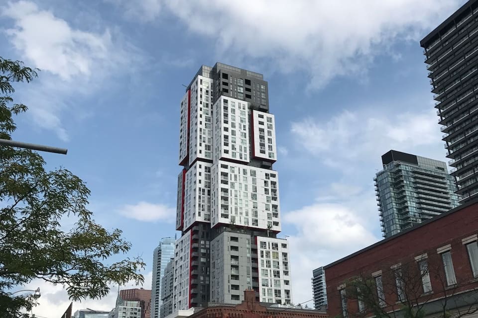 Panorama cittadino con un edificio alto dal design particolare, un edificio in mattoni rossi e un autobus.