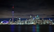 A city skyline at night with a prominent tower and a stadium.