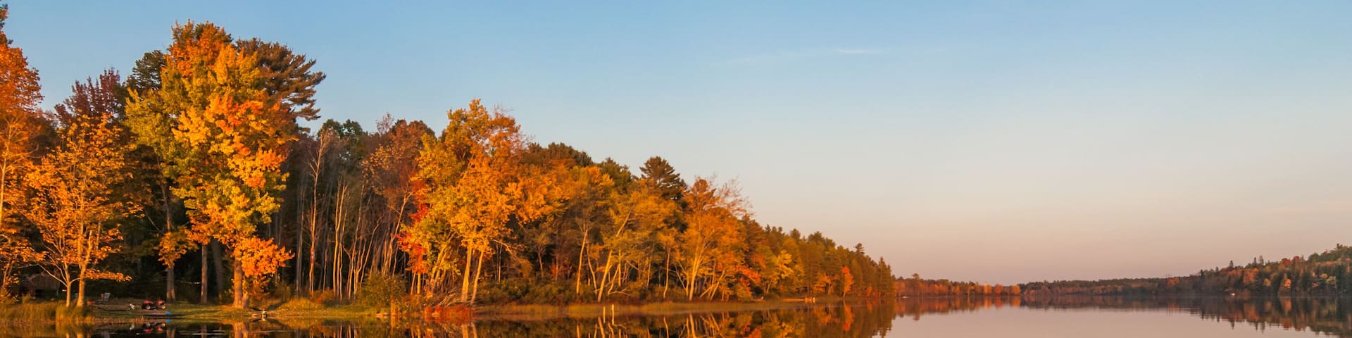 A calm lake reflecting autumn trees.