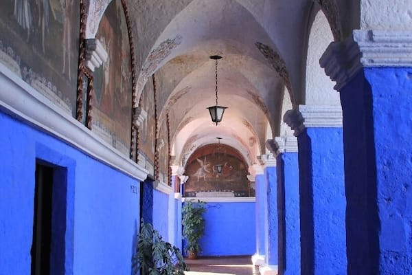 Ein Korridor mit blauen Wänden, gewölbter Decke und einer hängenden Leuchte.