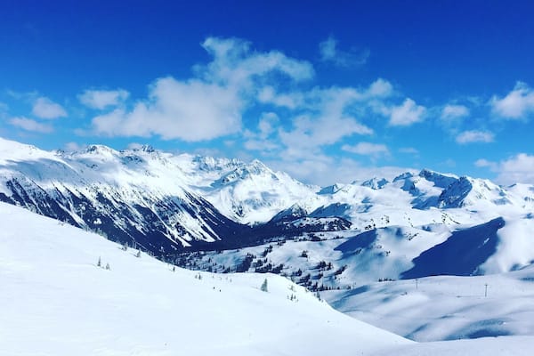 Une chaîne de montagnes enneigée sous un ciel bleu clair.