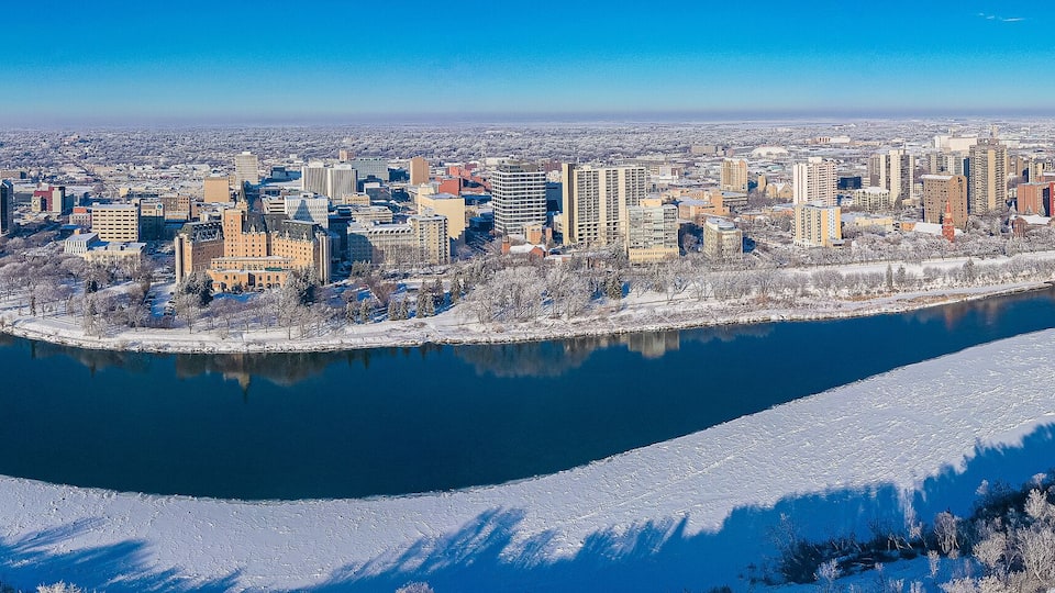 A cityscape with a river, bridges, and snow-covered trees.