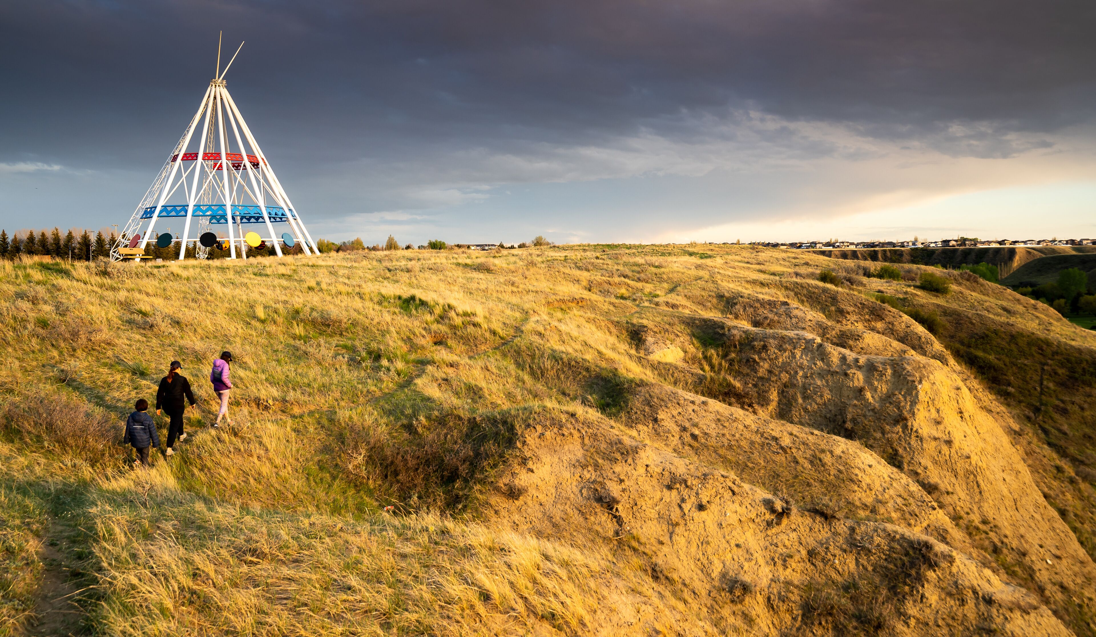 Medicine Hat Alberta Canada, May 13 2021: A family walks outdoors along a hiking trail in Seven Persons Coulee by the Sammis Tepee at sunset.