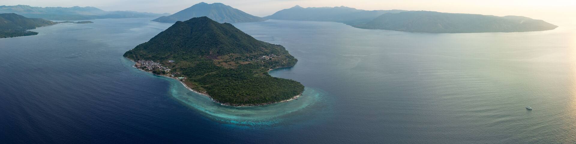 The volcanic island of Rita rises from the Pantar Strait near Alor, Indonesia. This distinctive island is surrounded by coral reefs that receive strong currents that run through the strait.