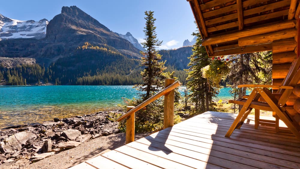 A wooden deck overlooking a turquoise lake with mountains in the background.
