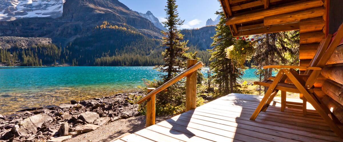 A wooden deck overlooking a turquoise lake with mountains in the background.