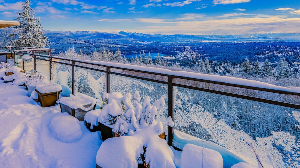 Scenic winter view across Fraser Valley, BC, Canada from snowbound penthouse patio with alpine mountains on horizon.