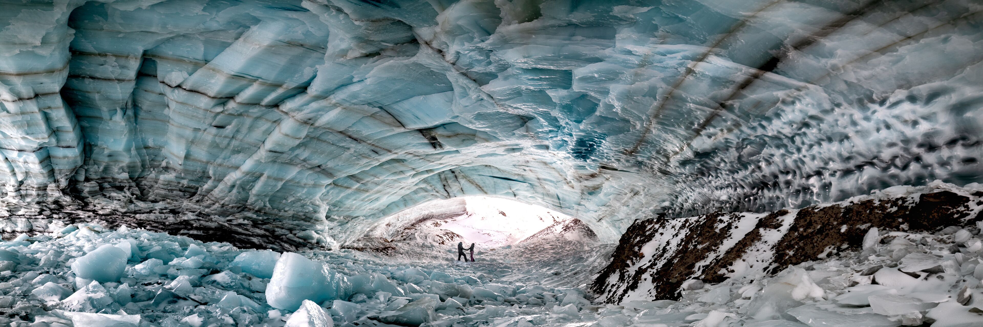 Historic ice cave located outside of Haines Junction in Kluane National Park, Yukon Territory with a couple, two people holding hands in love, romantic panoramic view. 