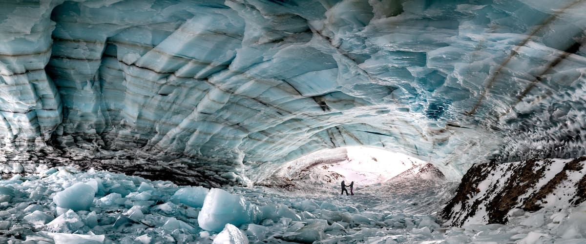 Historic ice cave located outside of Haines Junction in Kluane National Park, Yukon Territory with a couple, two people holding hands in love, romantic panoramic view.