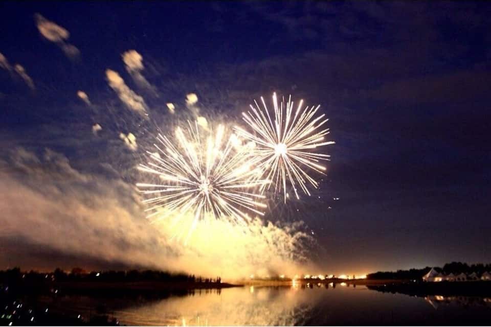Feuerwerk über einem Gewässer mit Spiegelungen.