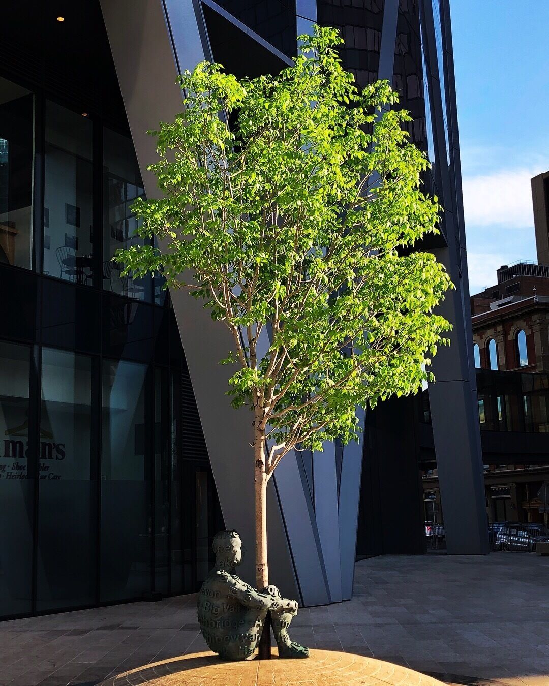 Calgary’s Dream bronze sculpture of a man hugging a live tree by Barcelona artist Juame Plensa outside The Bow tower.