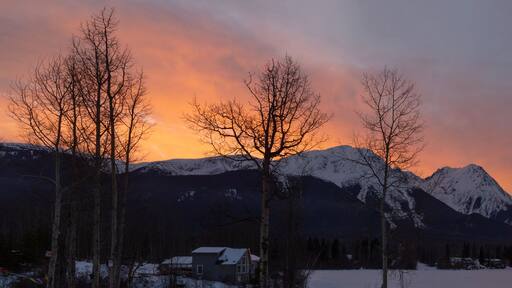Sky glowing pink over snow-capped mountains from Watson's Landing, Smithers, BC; Smithers, British Columbia, Canada