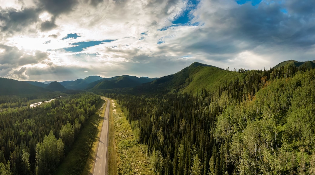 Beautiful Panoramic View of Scenic Road from Above surrounded by Lush Forest and Mountains. Aerial Drone Shot. Alaska Highway, West of Fort Nelson. Northern Rockies, British Columbia, Canada.