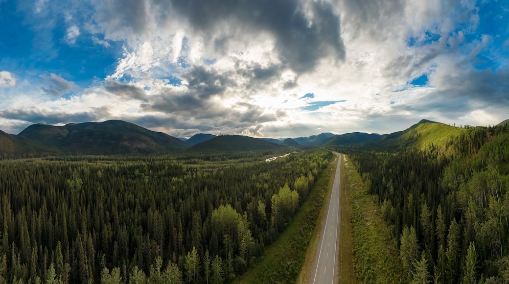 Beautiful Panoramic View of Scenic Road from Above surrounded by Lush Forest and Mountains. Aerial Drone Shot. Alaska Highway, West of Fort Nelson. Northern Rockies, British Columbia, Canada.