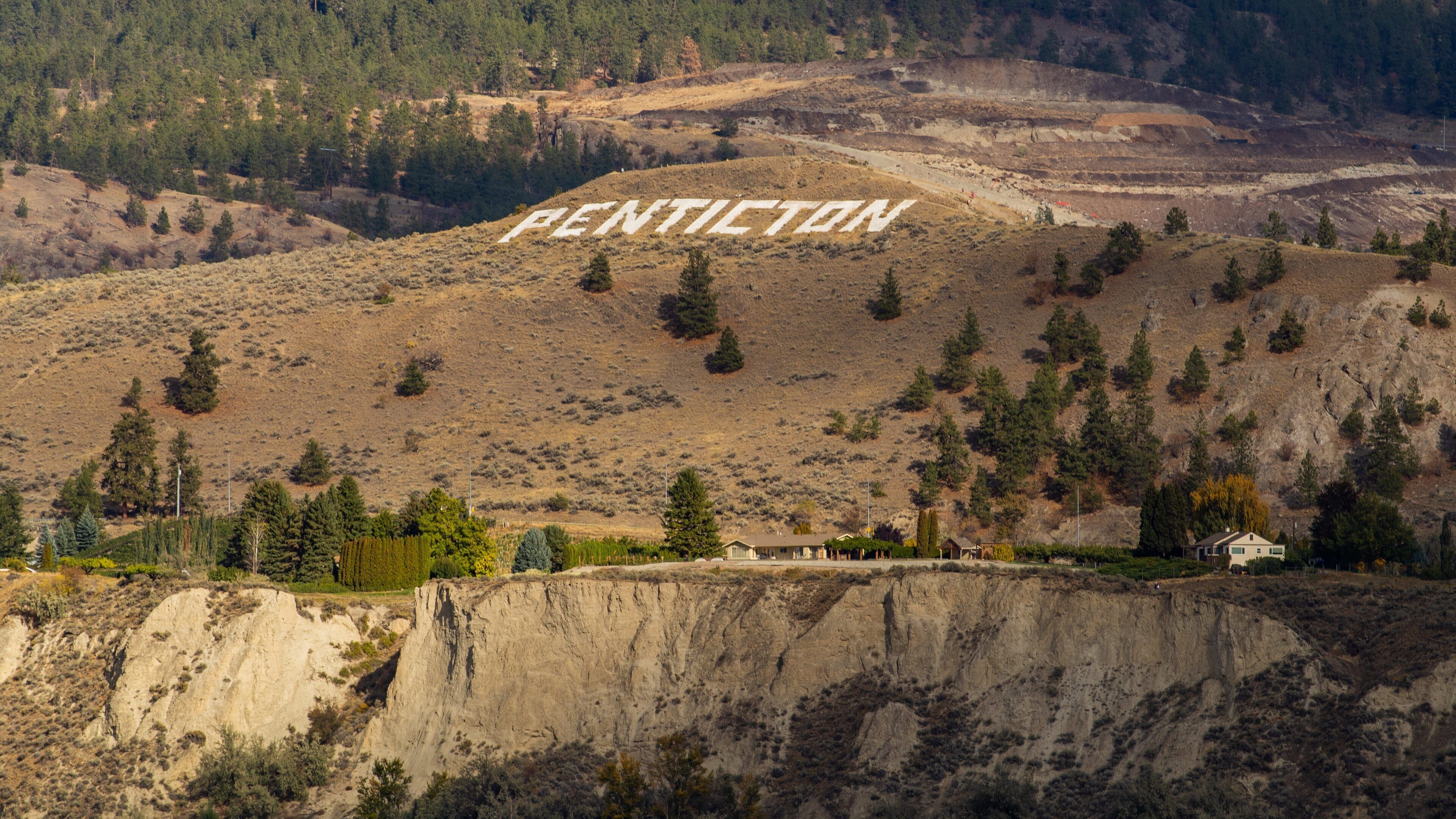 A mountainous landscape with the word "PENTICTON" carved into the hillside.