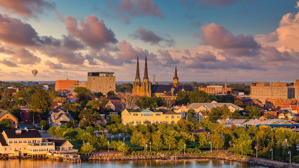 A cityscape with a prominent church, a hot air balloon, and a waterfront.