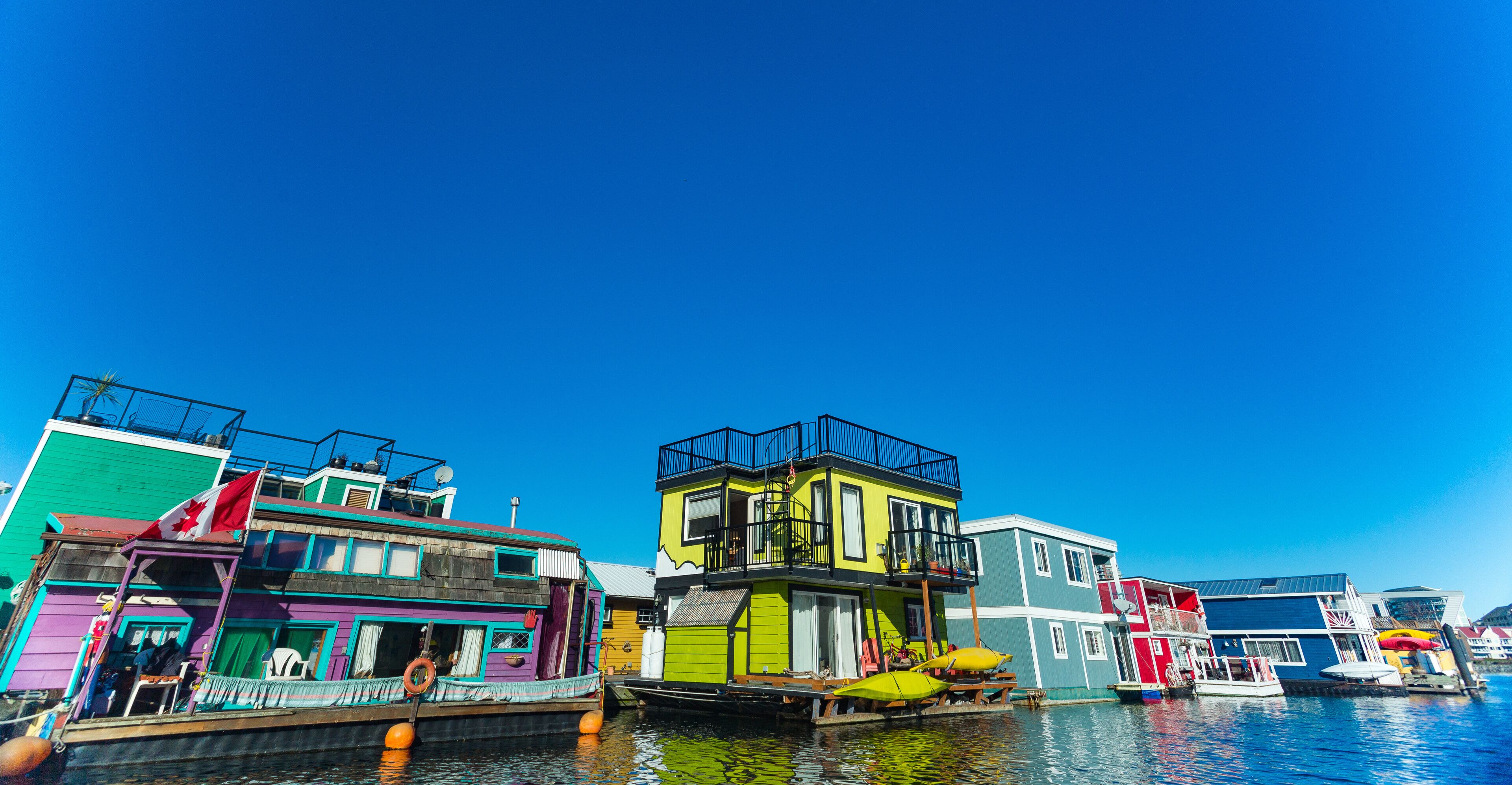Floating Home Village colorful Houseboats Water Taxi Fisherman's Wharf Reflection Inner Harbor, Victoria British Columbia Canada Pacific Northwest. Area has floating homes, piers, restaurants.