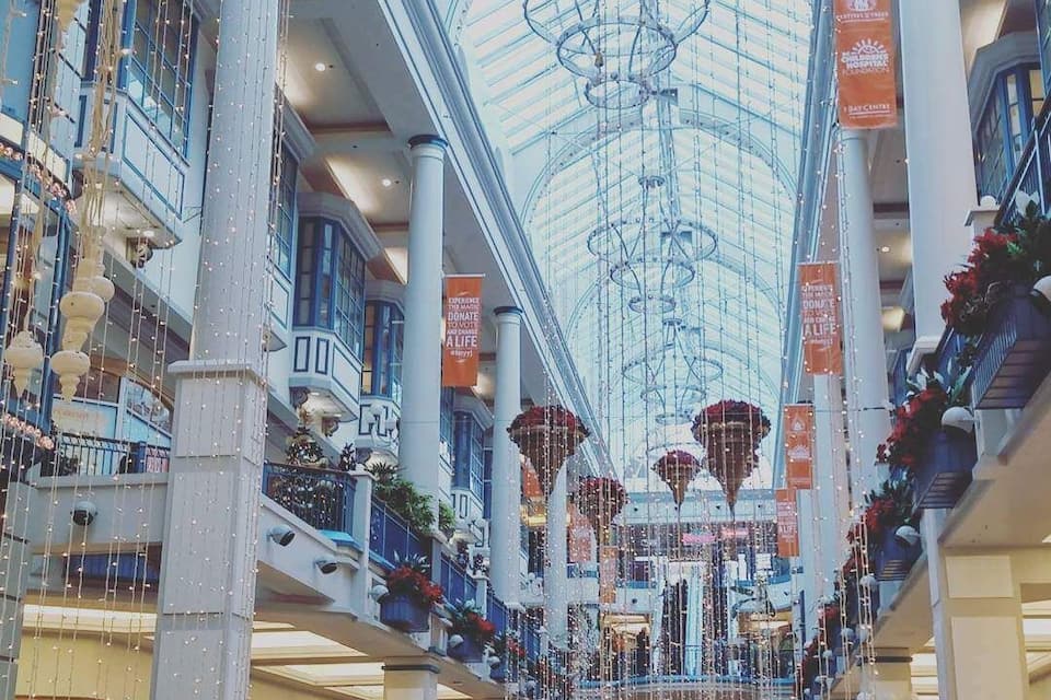 A multi-level shopping mall with a glass ceiling, hanging decorations, and banners.