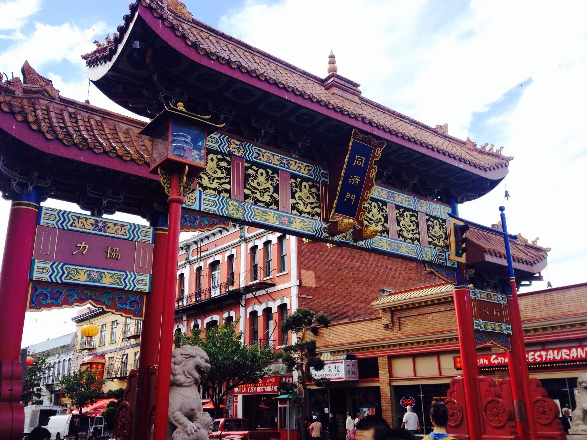 A traditional Chinese gate with ornate decorations and a lion statue.