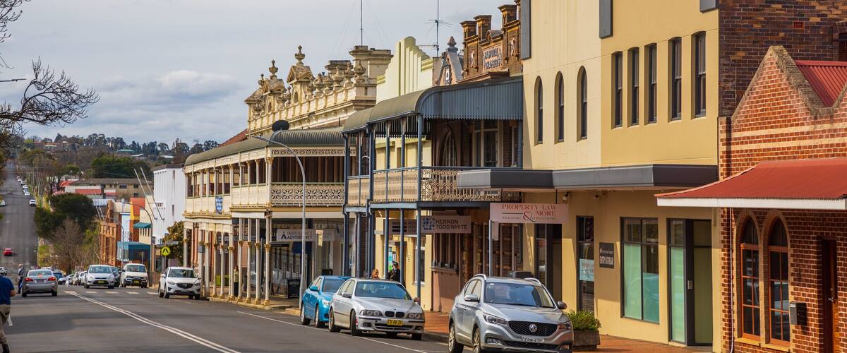 A street lined with historic buildings, including a prominent yellow building with a balcony and a brick building with a red roof.
