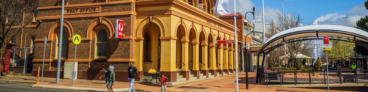 A historic post office building with a yellow facade and arched windows.