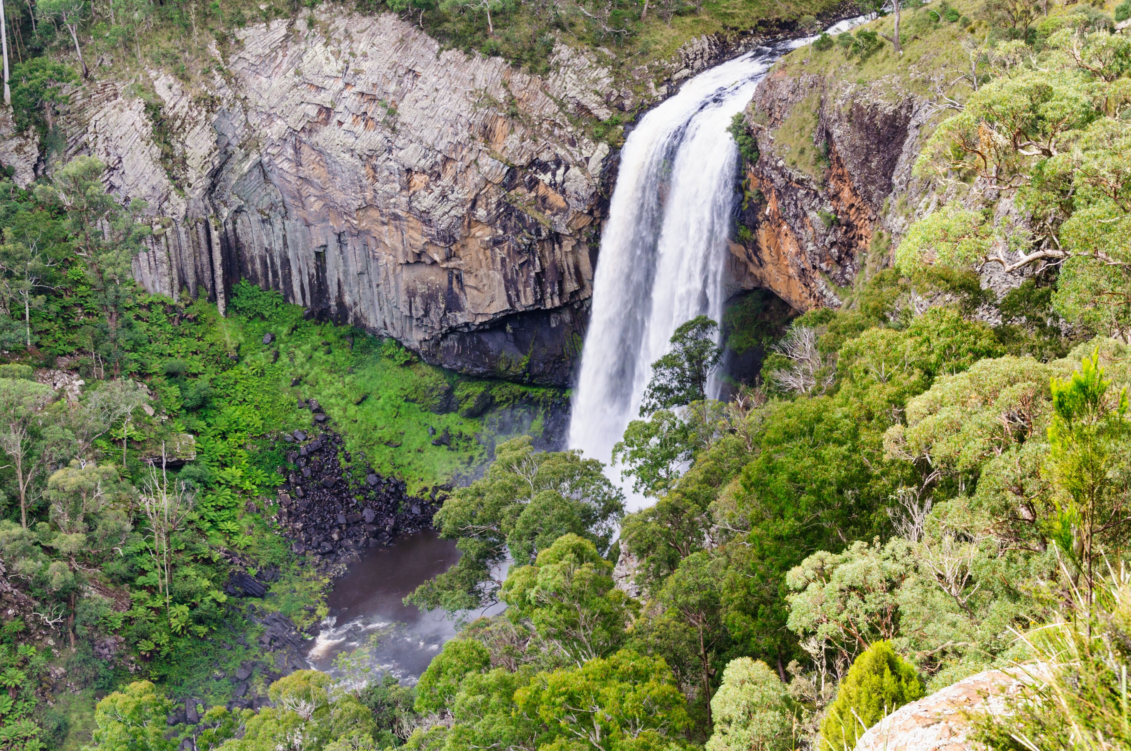 Une cascade se déversant le long d’une falaise rocheuse, entourée d’une végétation luxuriante.