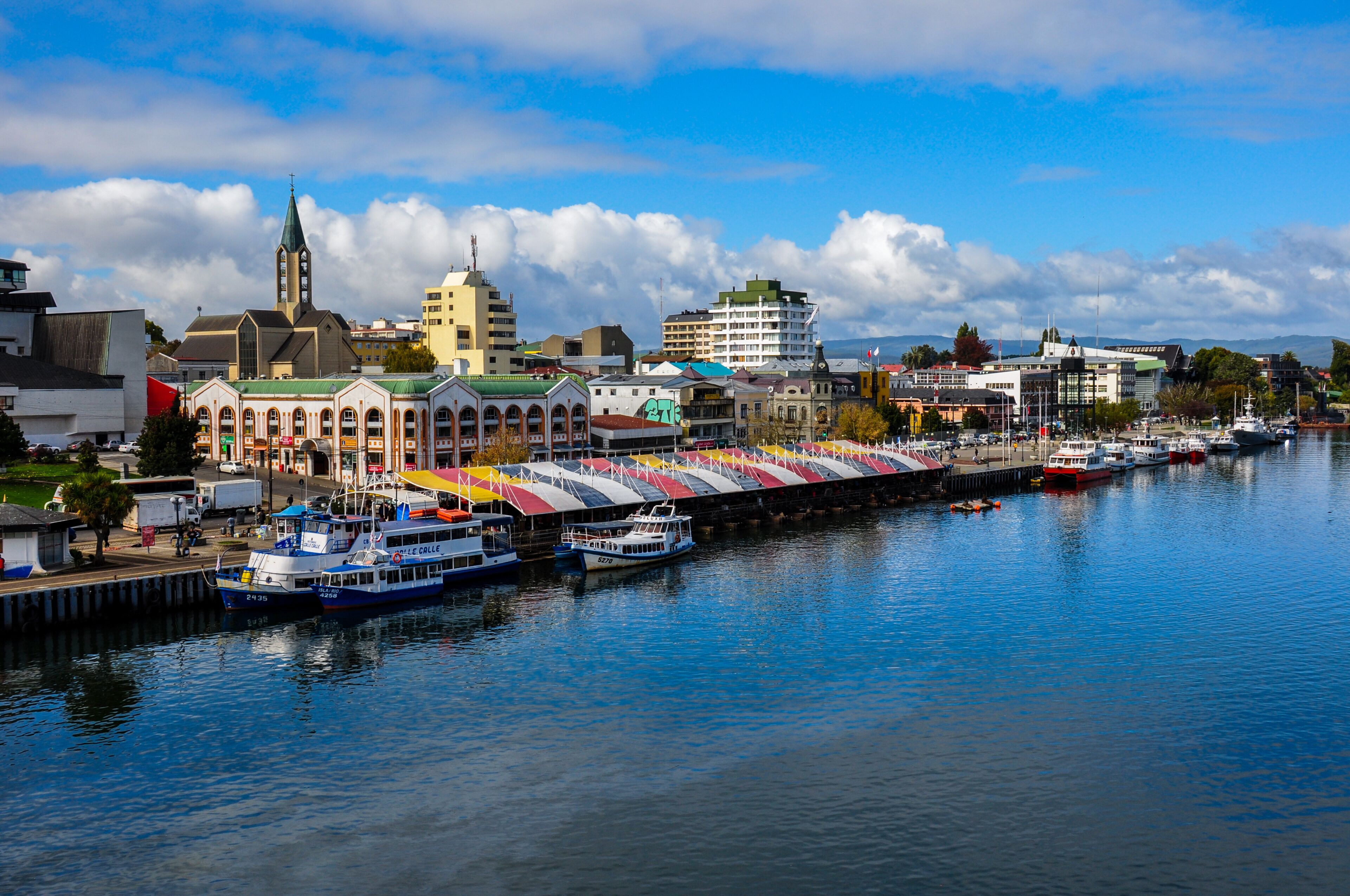 A harbor with boats, a church, and a colorful building with a green roof.
