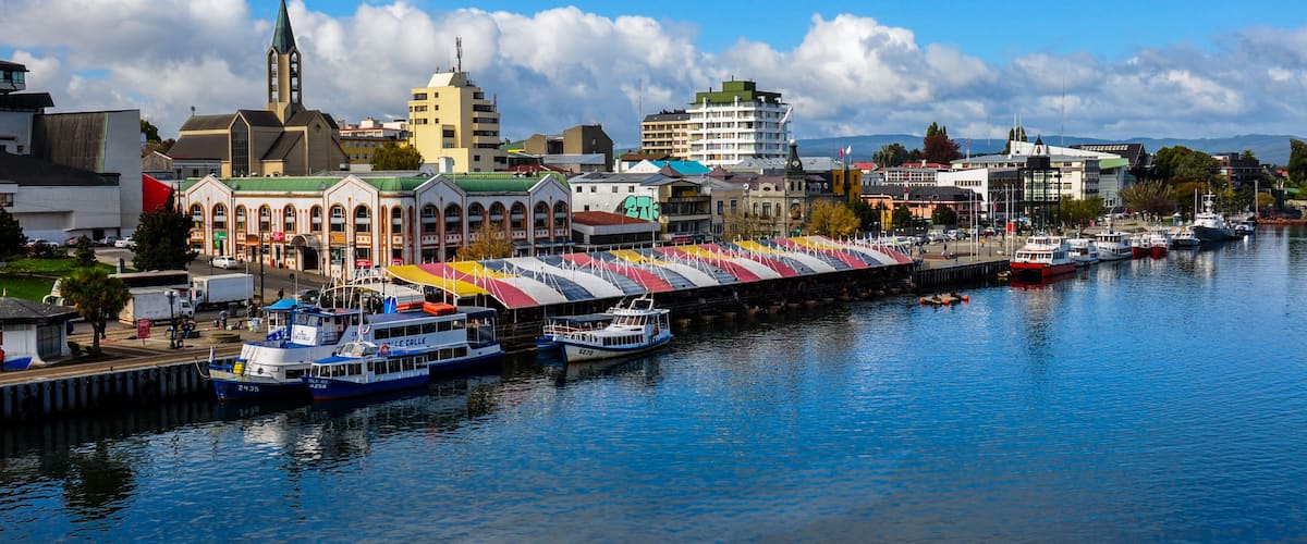 A harbor with boats, a church, and a colorful building with a green roof.