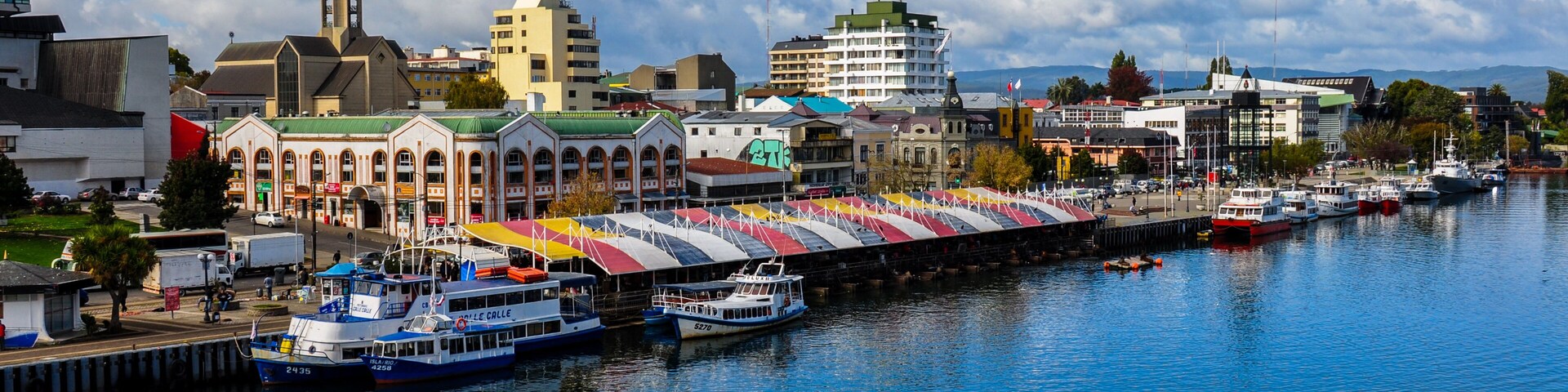 A harbor with boats, a church, and a colorful building with a green roof.