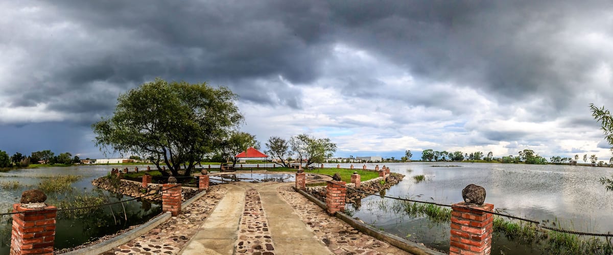 panoramic of natural pavilion in middle of a lake in cloudy day with grey clouds and beautiful tree in laguna grande zacatecas