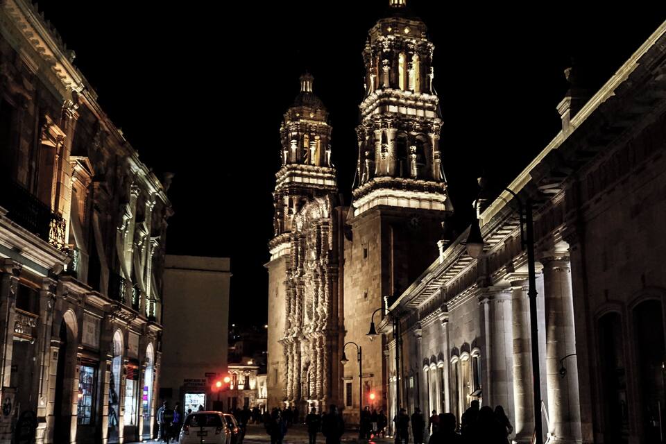A nighttime view of a historic building with two prominent towers, illuminated by artificial lighting.