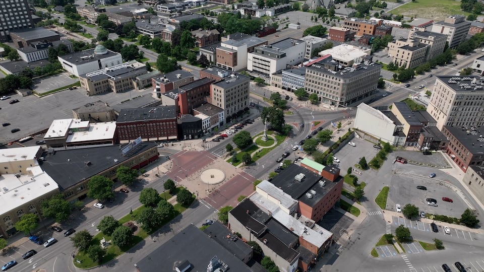 An aerial view of a cityscape with various buildings, roads, and a central roundabout.