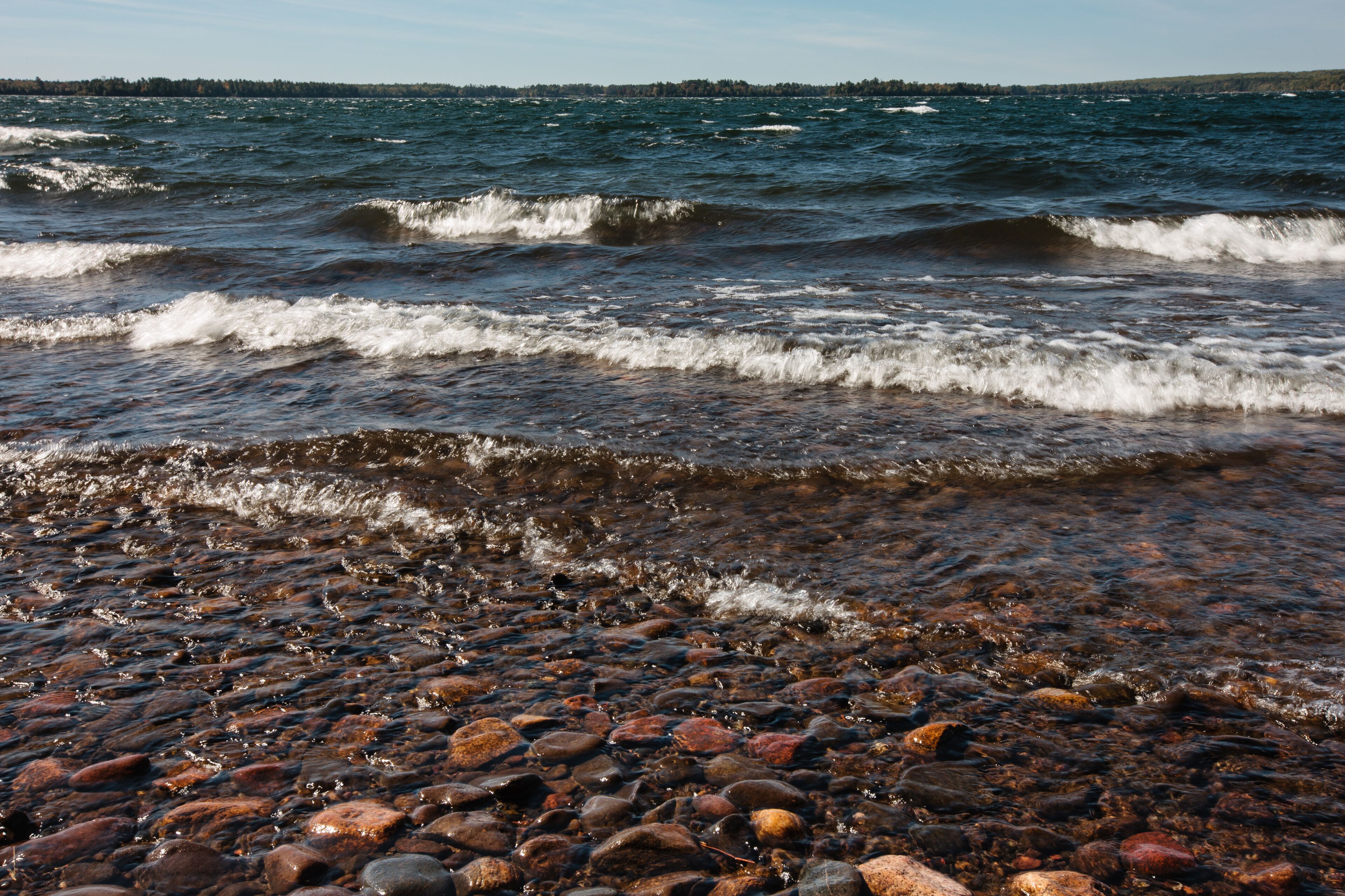 Waves rush over the eastern shoreline rocks of Trout Lake in Vilas County, near Boulder Junction, Wisconsin from a strong, south-westerly wind on a late-September morning.