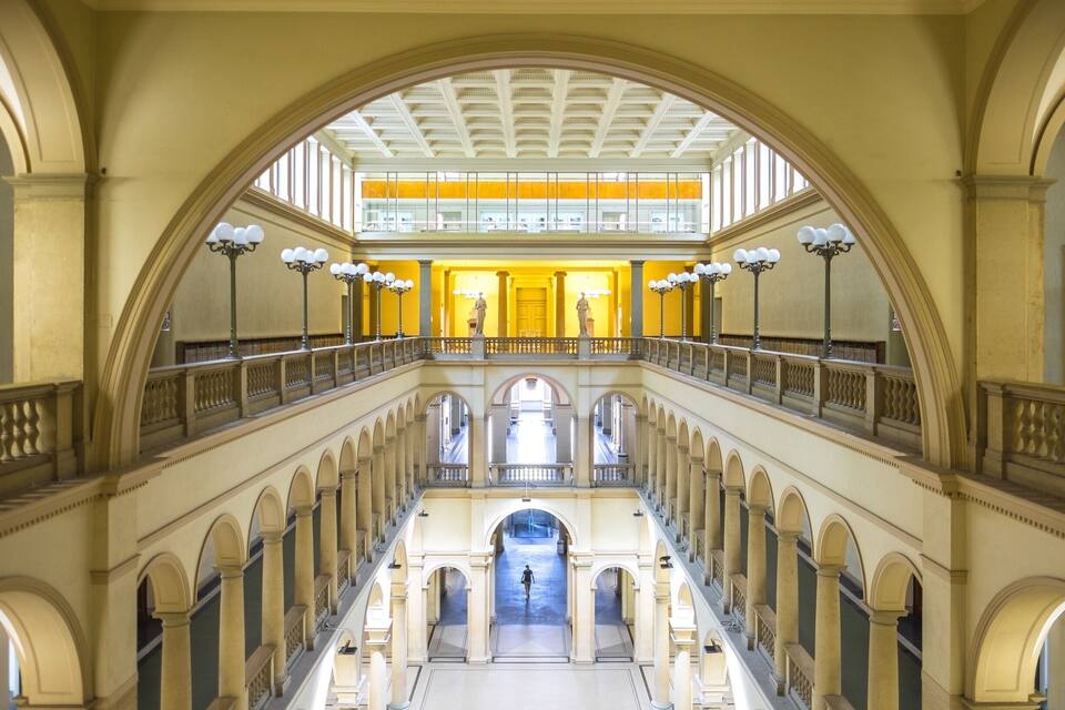 A grand interior with a central open space, arched balconies, and a high ceiling with decorative lighting.