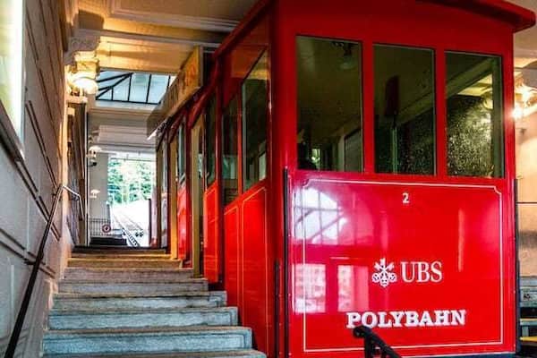 The train at the bottom Polybahn station.
Opened in 1889, The Polybahn, is a funicular railway in the city of Zürich. The line links the Central square with the terrace by the main building of ETH Zürich.
In 1970 the polybahn closed, and in 1996 was completely rebuilt.
There are 2 stops, with automatic 2 cars on a single track with a passing loop. The track is 176m long and rises 41m, with an average gradient of 23%.
It takes approx. 100 seconds to travel the distance and runs every 2 to 5 minutes.